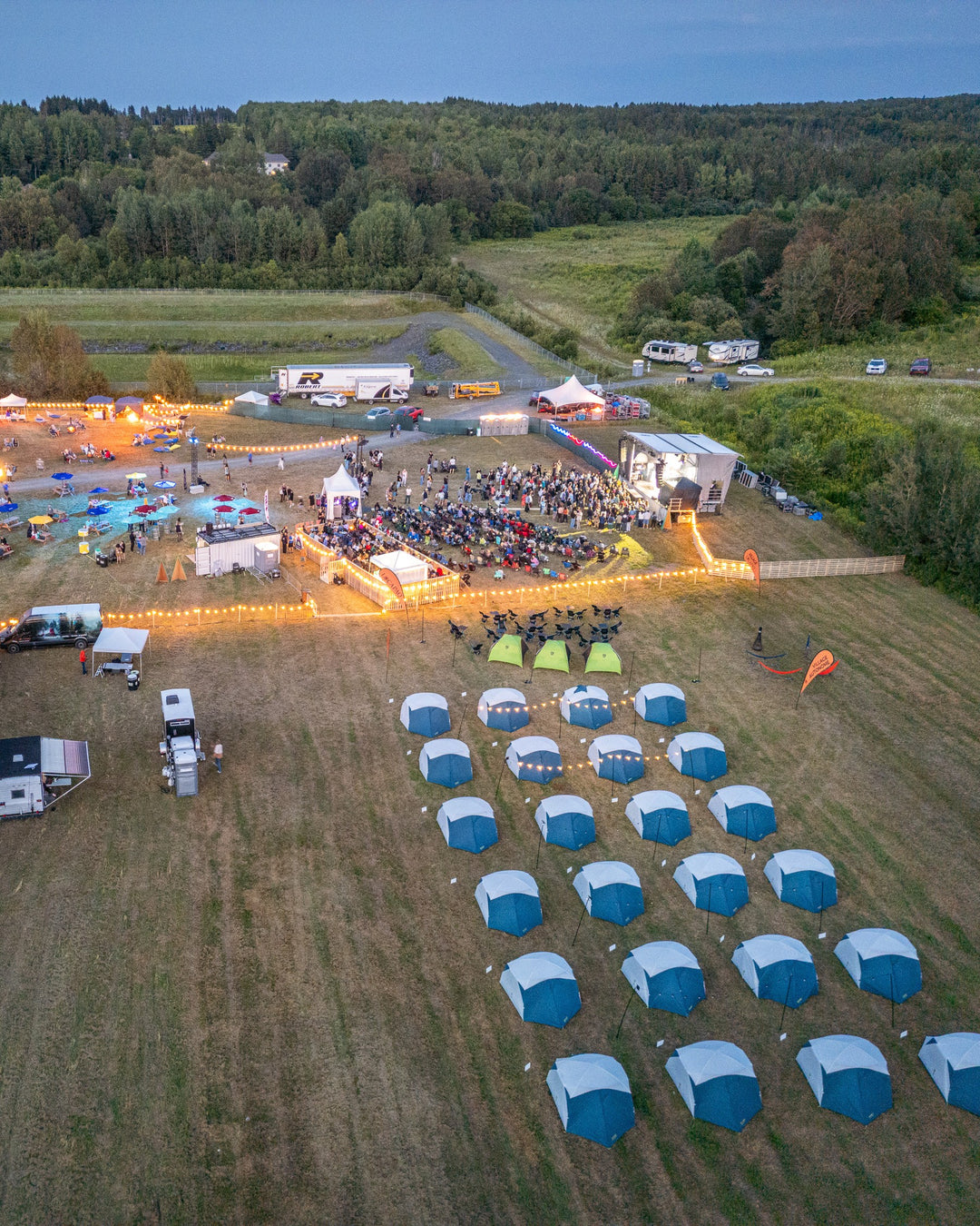 Village de tentes Locapaq installé à côté de la scène d'un festival en soirée